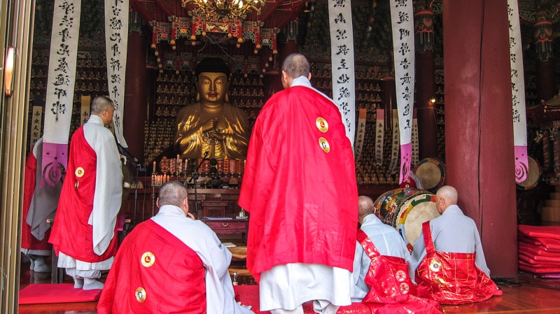 Monks in prayer inside the main Buddha Hall at Bongwonsa Temple in Seoul