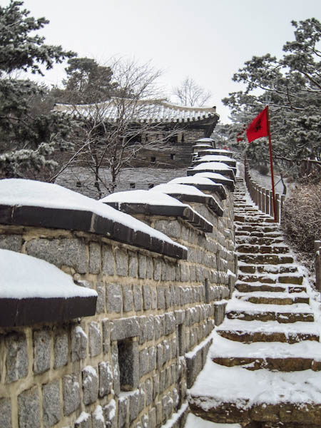 Walking along the wall on snowy steps at Hwaseong Fortress
