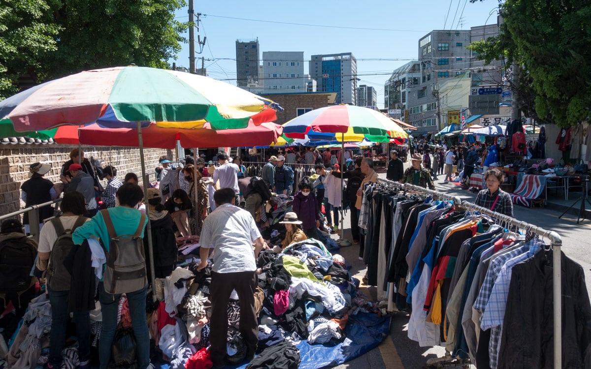 Shoppers digging through piles of clothes at Dongmyo Flea Market