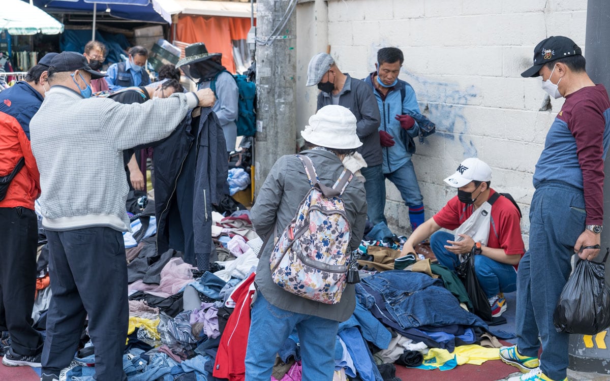 Shoppers look through piles of secondhand clothes laid out on the ground at Dongmyo Flea Market in Seoul.
